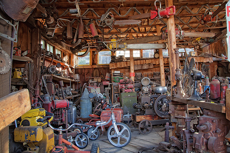 old chainsaws hang from the rafters and old outboard motors and tricycles can be seen